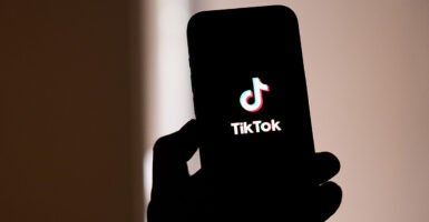 A silhouetted cellphone displays the social media app TikTok