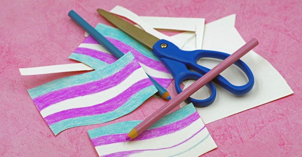 small transgender paper flags made by a student with paper, colored pencils, and a small pair of scissors