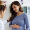 A pregnant woman confers with a medical professional.