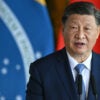 China's leader, Xi Jinping, stands behind a podium in front of the China and Brazil flags.