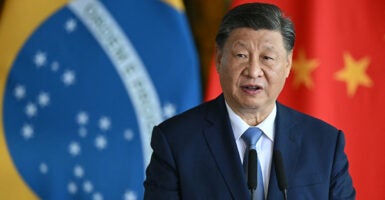 China's leader, Xi Jinping, stands behind a podium in front of the China and Brazil flags.