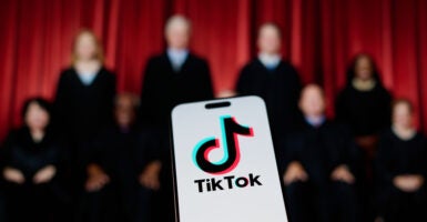 A semi-silhouetted photo of the justices of the Supreme Court with the logo of TikTok on a cellphone superimposed upon it