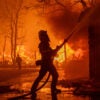 A fireman douses flames of the California inferno as best he can with a hose in California.