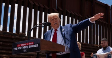 Donald Trump speaks at the U.S.-Mexico border in Arizona next to a very high fence