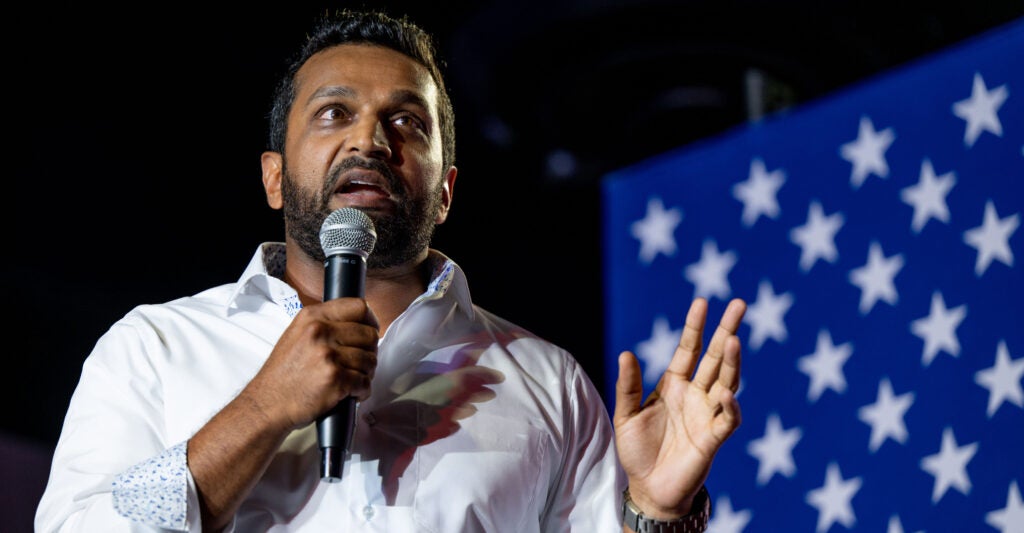 FBI Director-designate Kash Patel speaking into a microphone next to a U.S. flag