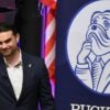 Ben Shapiro stans at a podium in front of an American flag.