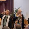 Two reverends stand in front of the congregation and participate in the Holy Communion.