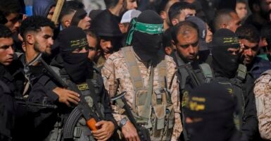 Hamas militants stand while holding machine surrounded by a crowd of people.