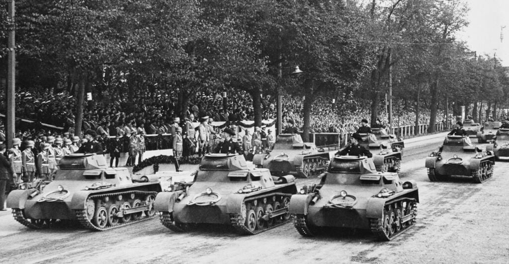 German tanks in formation roll down a street during World War II.