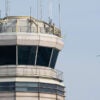 Airplanes flying past an air traffic control tower.