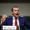 Pete Hegseth raises his arms and talks in an animated fashion during a Senate hearing