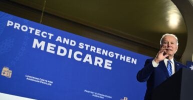 President Joe Biden speaks while standing next to a banner.