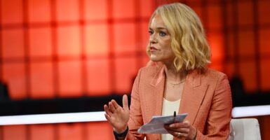 Katherine Maher, CEO of NPR, sits in a chair on stage and motions with her hands while talking.