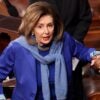 Nancy Pelosi stands inside the U.S. Capitol Building as she is assisted by aides.