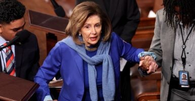 Nancy Pelosi stands inside the U.S. Capitol Building as she is assisted by aides.