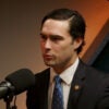 Rep. Brandon Gill in a dark suit sitting next to a microphone