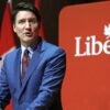 Justin Trudeau stands at a podium next to a banner that says, "Liberal".