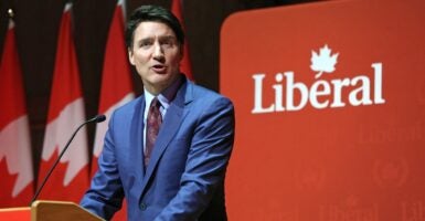 Justin Trudeau stands at a podium next to a banner that says, 