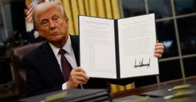 Donald Trump holds up with both hands an executive order he signed.