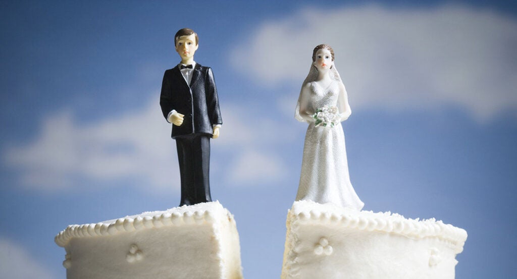 Wedding cake with bride and groom toppers splits down the middle