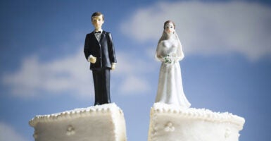 Wedding cake with bride and groom toppers splits down the middle