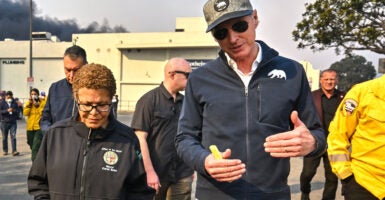 Mayor Karen Bass chats with Gov. Gavin Newsom, who is in a blue jacket and baseball cap, while surveying damage during the Palisades Fire