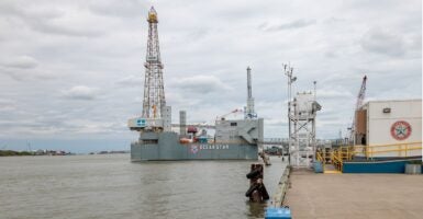 An offshore drilling rig stands in the middle of an ocean.