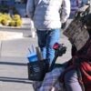 A homeless man sits on a sidewalk holding up a sign.