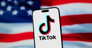 TikTok logo on a cellphone superimposed over an American flag