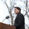 Justin Trudeau stands at a podium outdoors.