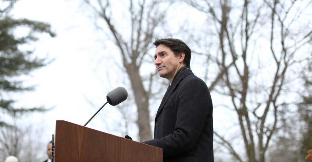 Justin Trudeau stands at a podium outdoors.