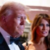 President Donald Trump in a tuxedo stands next to his wife Melania in a black dress at an event.