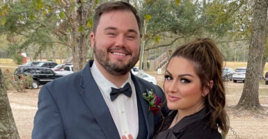 Zack Knotts in a black tie and boutonnière with his wife, Lindsay Knotts