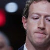 Mark Zuckerberg close up in a suit staring down, looking pensive