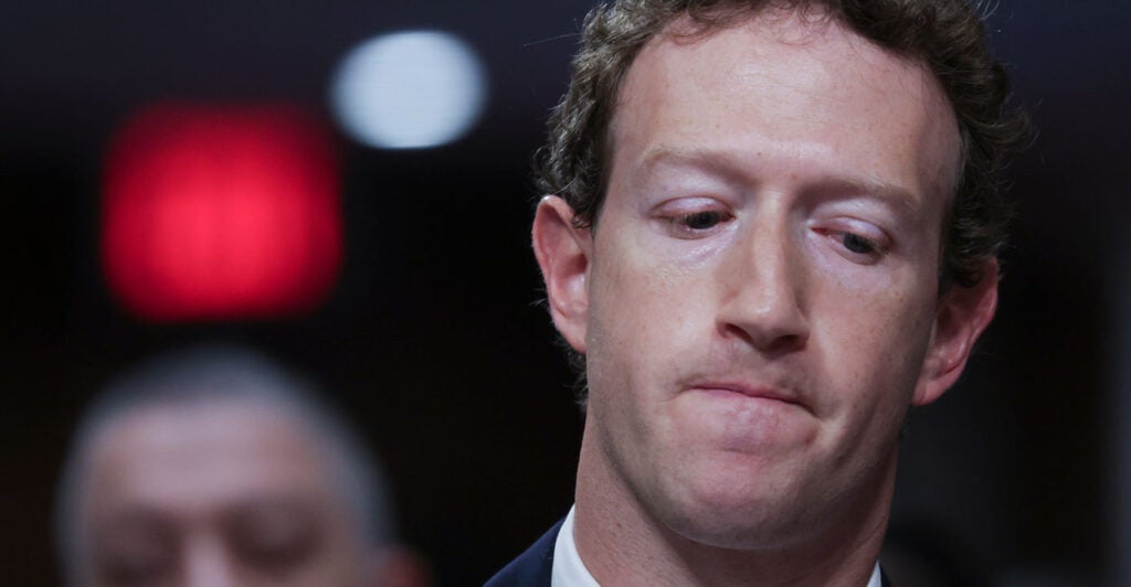 Mark Zuckerberg close up in a suit staring down, looking pensive