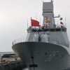 A Chinese navy ship sits at port with a flag flying.