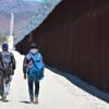 Illegal aliens walk on the U.S. side of the border wall in Jacumba Hot Springs, Calif., on June 5, 2024.