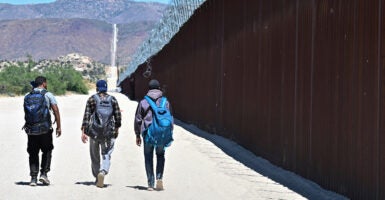 Illegal aliens walk on the U.S. side of the border wall in Jacumba Hot Springs, Calif., on June 5, 2024.