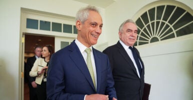 Rahm Emanuel stands wearing a blue suit and beige necktie.