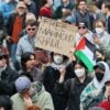 A person surrounded by protesters holds up a handmade sign that says "Free Mahmoud Khalil"