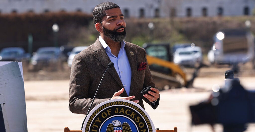 Jackson Mayor Chokwe Antar Lumumba speaks at a podium in a suit