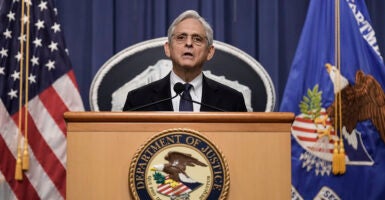 Attorney General Merrick Garland speaks at a podium with the words 